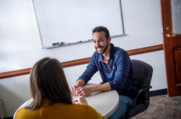 Two people talking at a desk