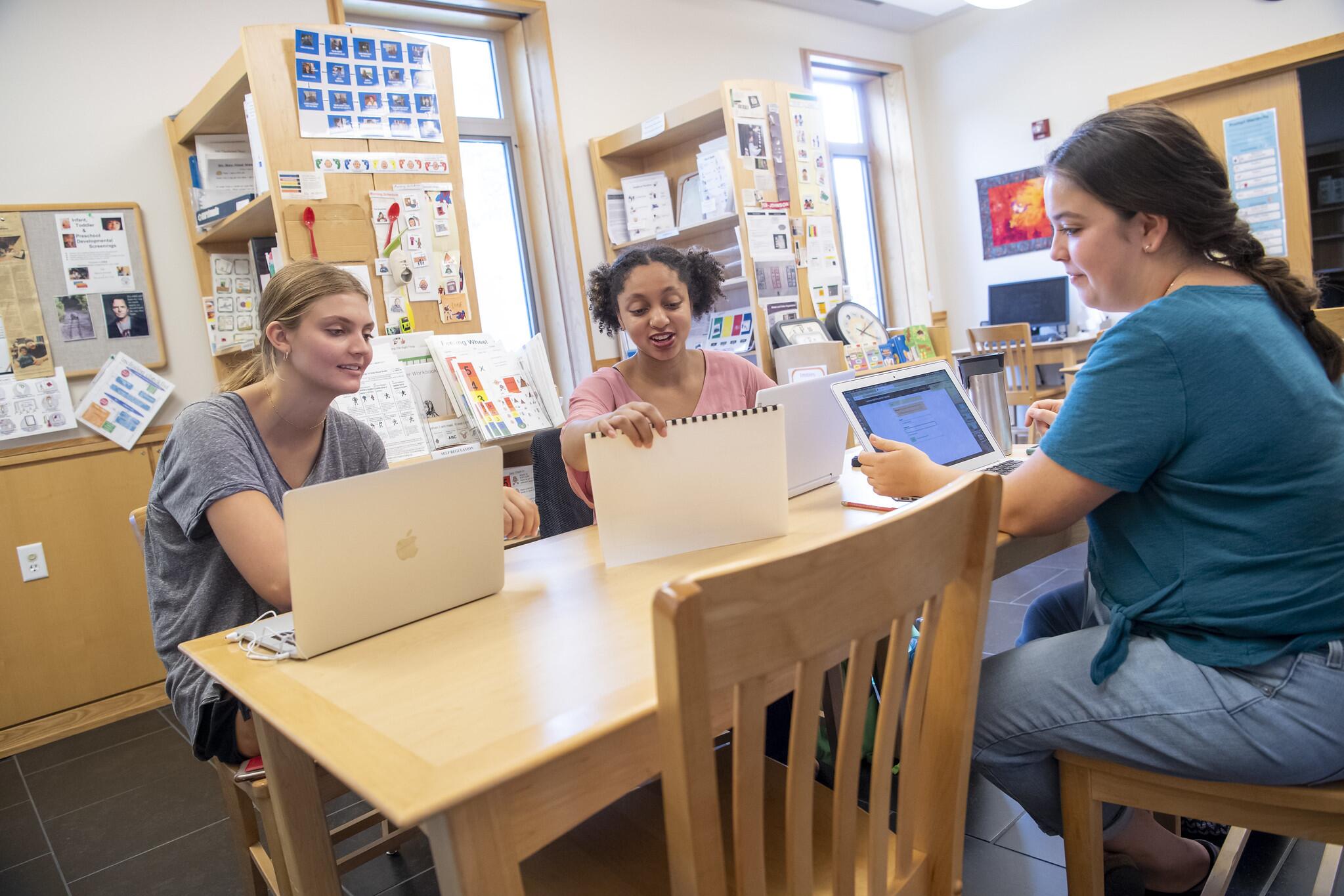 Group of students at a desk looking at calendars.