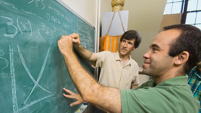 Students writing on a chalkboard