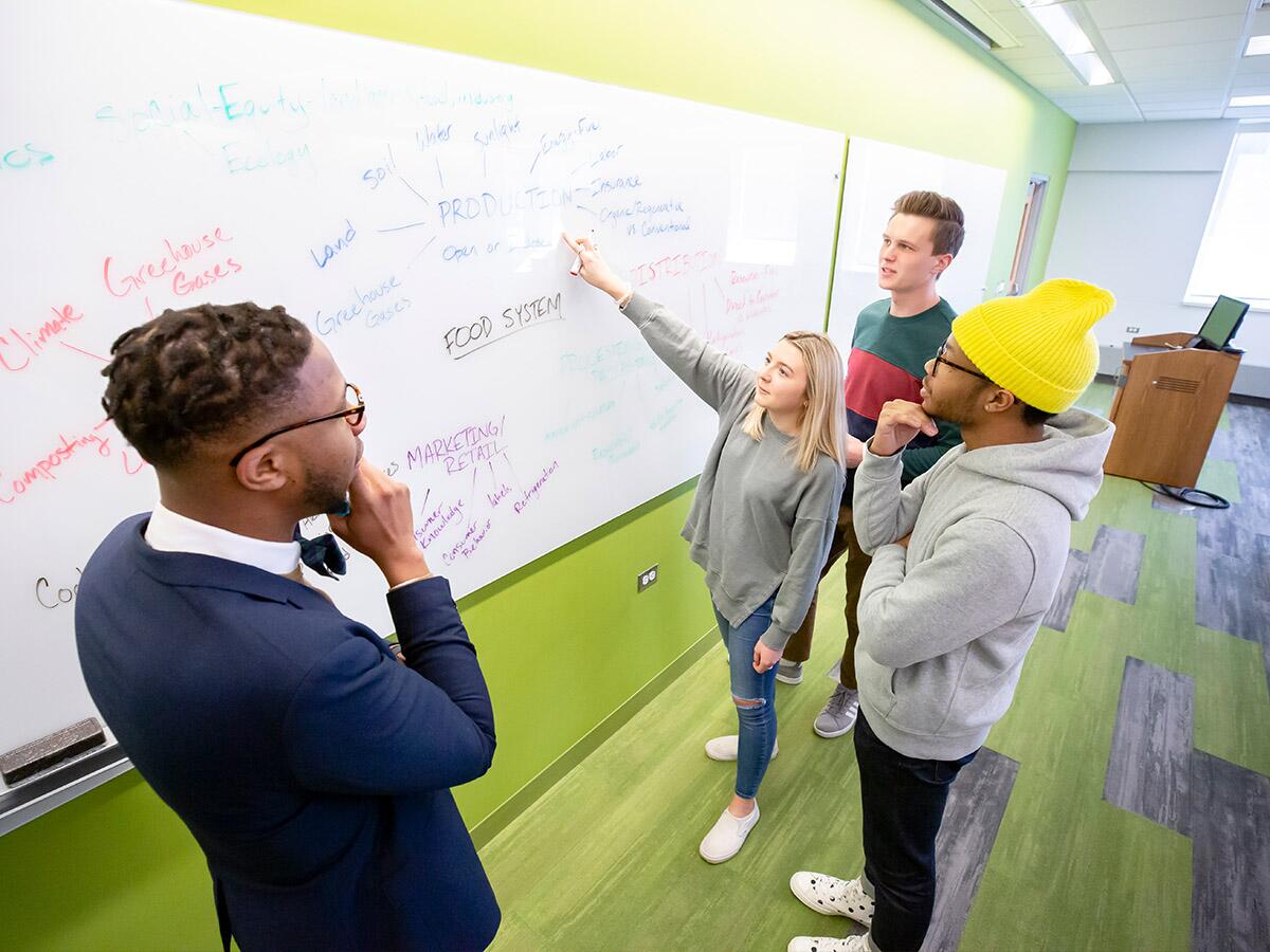 Groups of students brainstorming around a whiteboard.